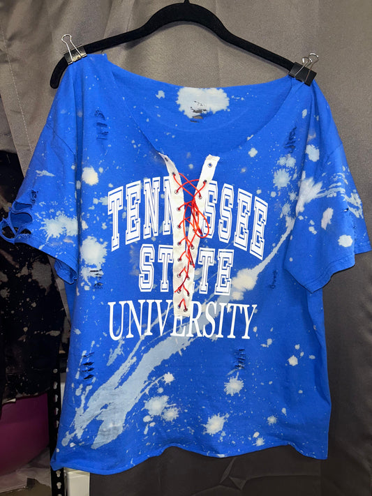 Blue t-shirt with white splatter design and 'Tennessee State University' text on a hanger.