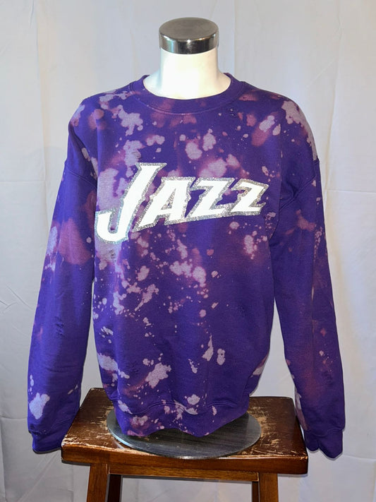 Purple tie-dye sweatshirt with 'Jazz' text on a mannequin against a white wall.