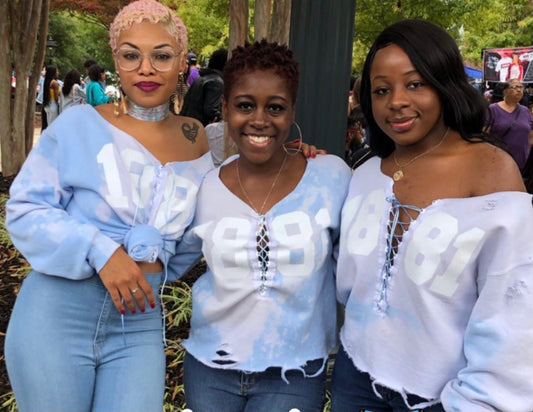 Three Spelman alumnae smiling together at the 2024 Spelman College Reunion, wearing custom Cami Co. Lace sweaters and celebrating sisterhood on campus near the historic Spelman promenade.