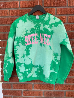 Green tie-dye sweatshirt with 'SKEE WEE' text on a brick wall background